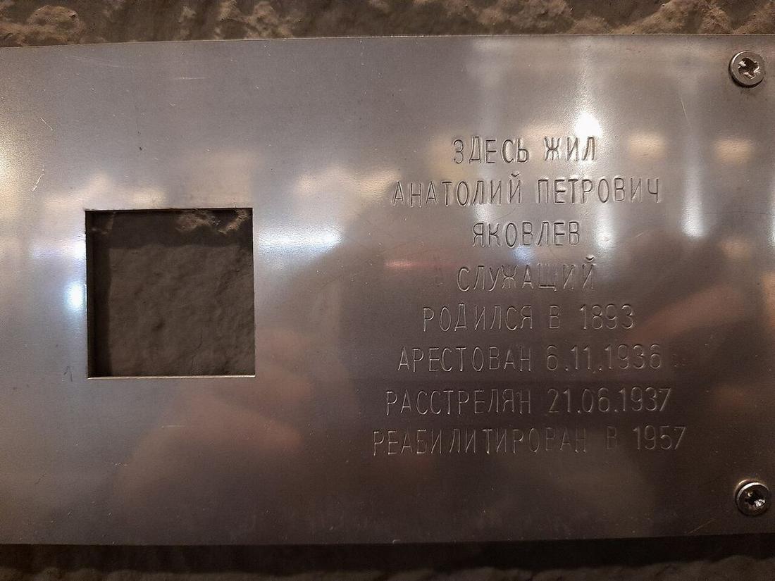 Стальная табличка «Последнего адреса» с квадратной прорезью и выбитым текстом: «Здесь жил Анатолий Петрович Яковлев», профессия, даты рождения, ареста, расстрела и реабилитации
